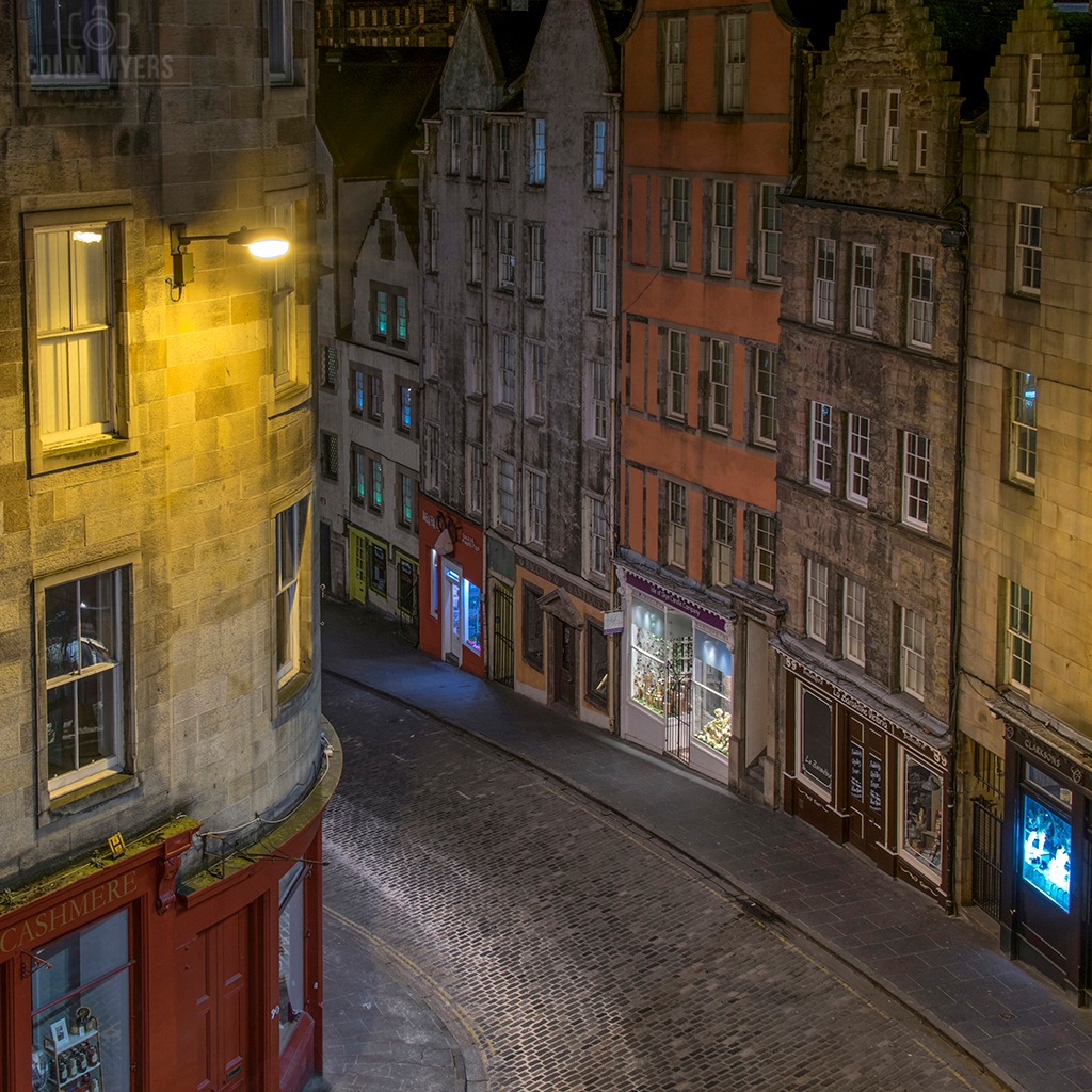 Historic cobblestone street with old stone buildings at night in Edinburgh