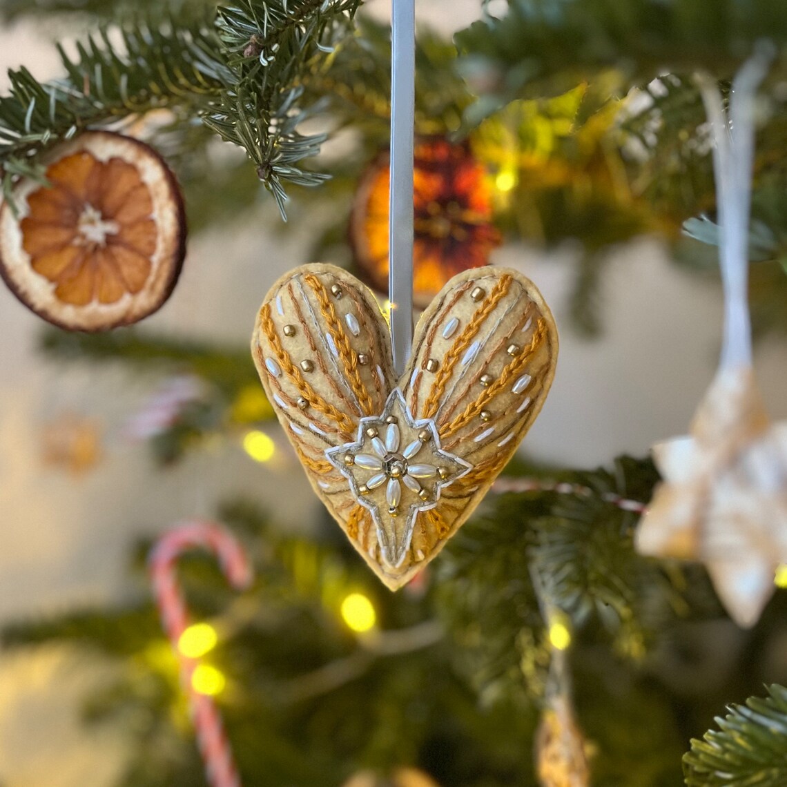 Gold heart ornament hanging on a Christmas tree with lights and holiday decorations