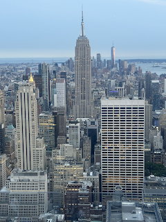 Aerial view of New York City skyline with Empire State Building prominently centered among dense urban skyscrapers