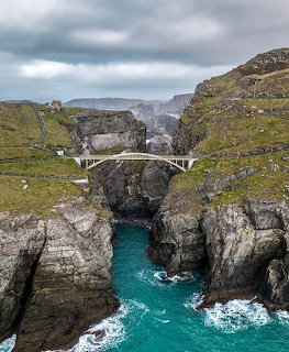 Footbridge over a rocky coastal gorge with turquoise sea water at Mizen Head, County Cork