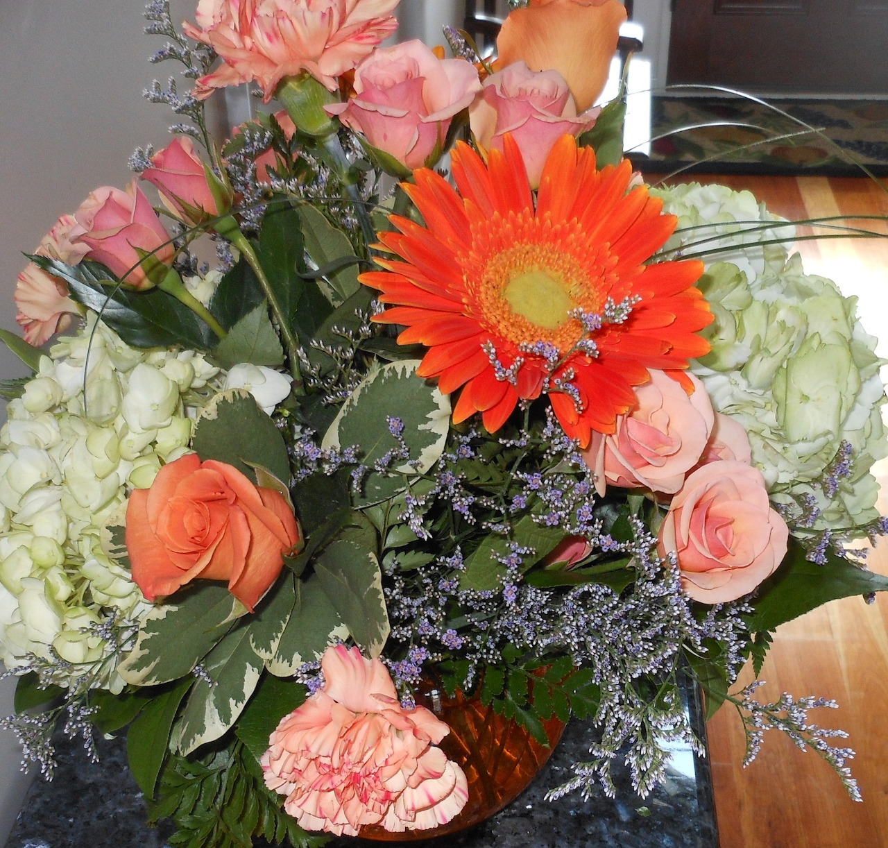 Close-up of a mixed bouquet with pink roses, white hydrangeas, and an orange gerbera daisy