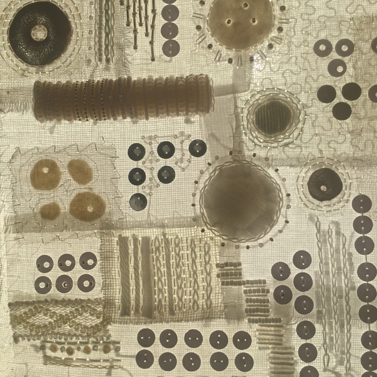 Sepia abstract textile design with buttons, stitched lines, and patterned fabric squares
