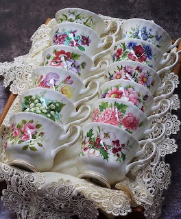 Vintage Royal Albert teacups with floral patterns arranged on white lace doily