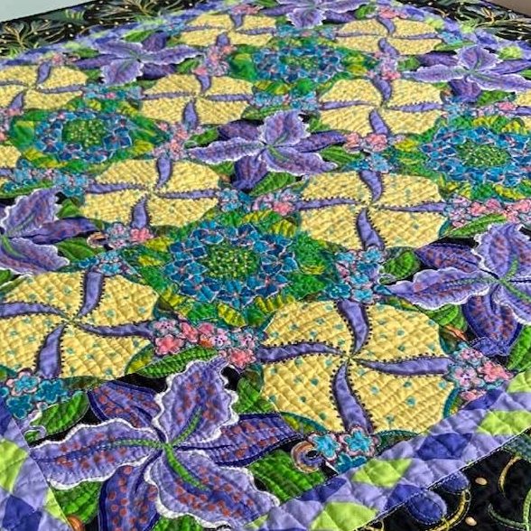 Colorful patchwork quilt with purple, yellow and green fabric squares in geometric pattern