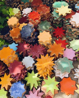 Colorful star-shaped decorative tiles scattered on a light surface in various bright colors
