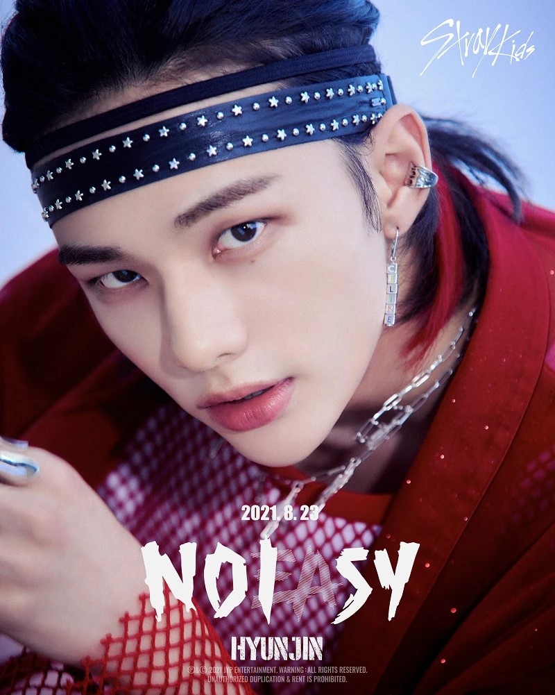 Young man with dark hair wearing red outfit, black star headband, silver chain and ear piercings