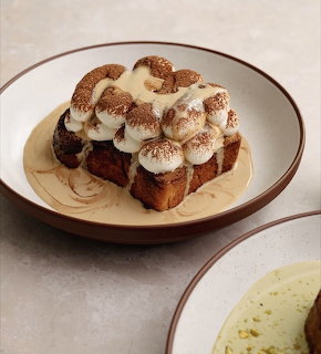 Tiramisu dessert with layered cream and cocoa powder on a beige plate