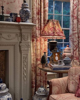 Elegant interior with fireplace, floral curtains, lamp, window, and porcelain decor