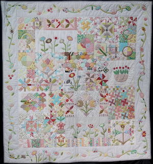 Patchwork quilt with embroidered flowers, birds, houses and garden motifs in soft pastel colors