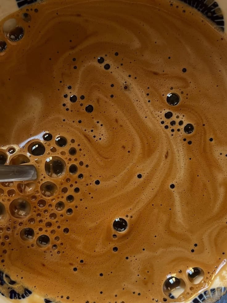 Close-up of coffee surface with creamy swirls and foam bubbles