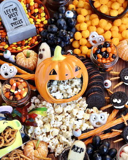 Halloween party table with jack-o-lantern, candy corn, ghost cookies, and assorted spooky treats