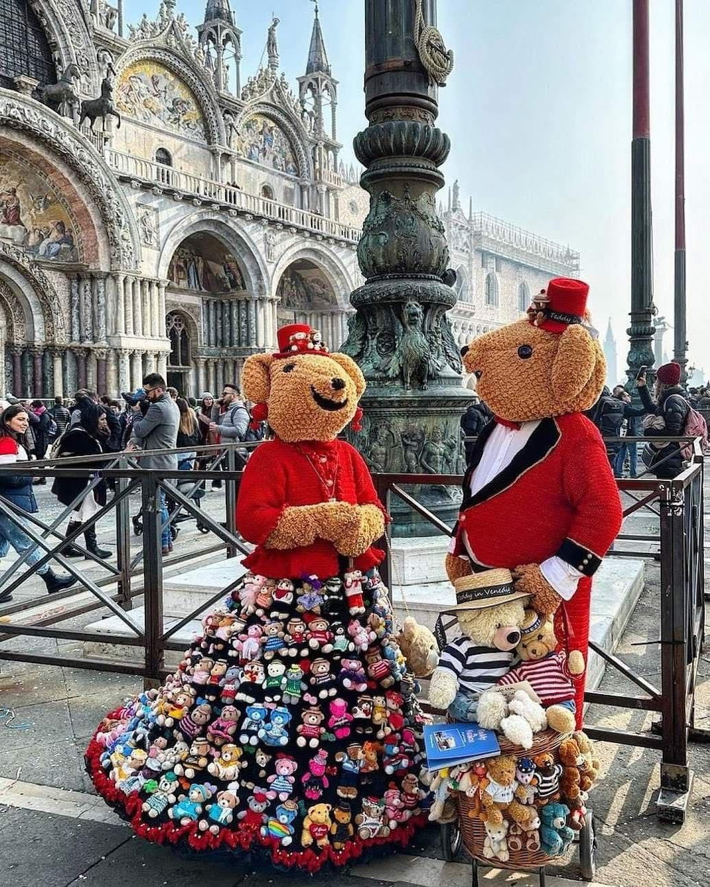 Two teddy bear mascots in red carnival costumes with ornate decorations at Venice St. Mark's Square