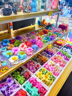 Colorful flower hair clips displayed in trays on wooden shelves in a shop