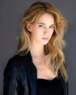 Portrait of blonde woman in black leather jacket on grey background