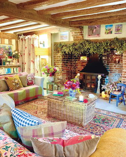Cozy boho living room with brick fireplace, wood beams, patterned rugs, and colorful patchwork sofas