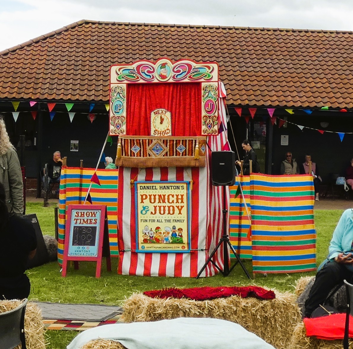 Colorful Punch and Judy puppet show booth at an outdoor fair with striped panels and bunting
