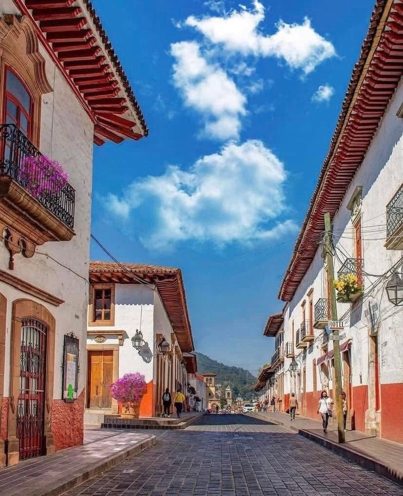 Colonial street in Pátzcuaro with white buildings, red tile roofs, and mountain backdrop
