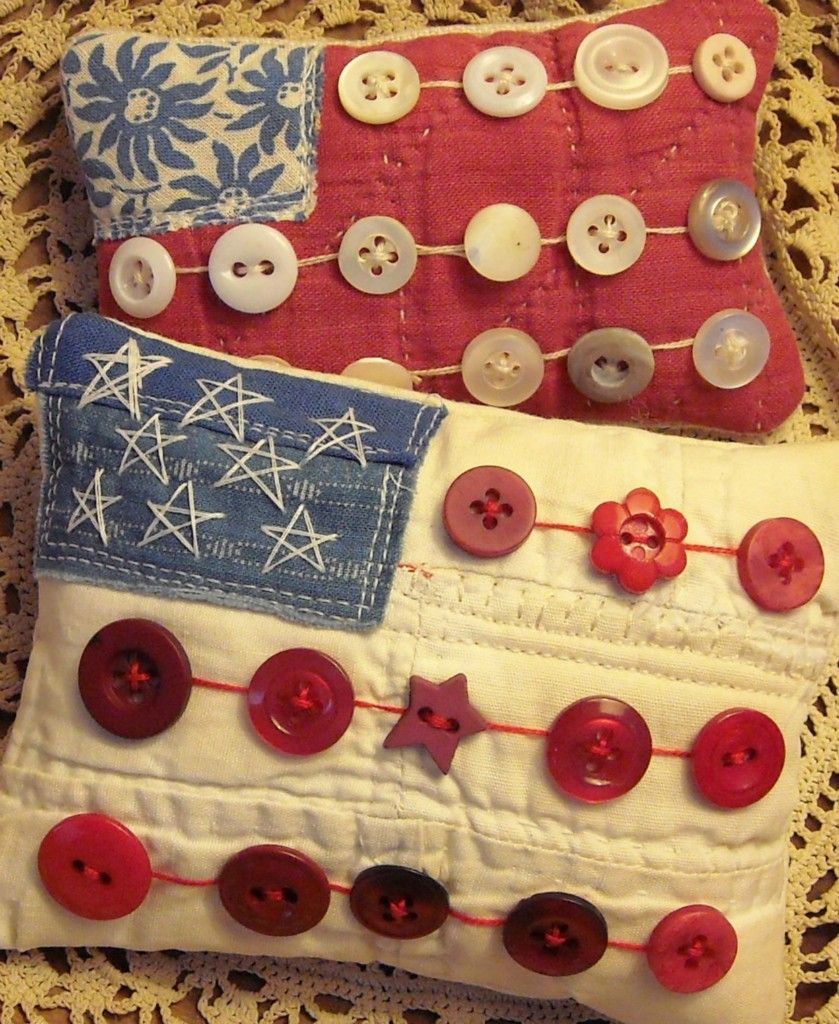 Two handmade patriotic American flag pillows decorated with red and white buttons on lace background