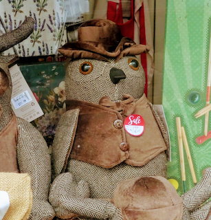 Vintage stuffed teddy bear wearing brown vest and top hat in shop window