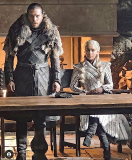 Jon Snow and Daenerys Targaryen standing at a wooden table in medieval attire from Game of Thrones