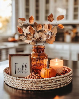 Autumn centerpiece with dried leaves in amber vase, pumpkin, candle and Fall sign on woven tray