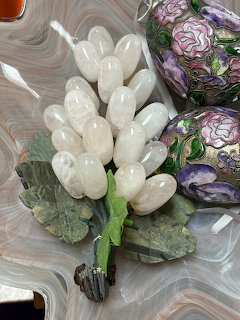 Decorative quartz grape cluster with leaves on a polished stone surface beside painted eggs