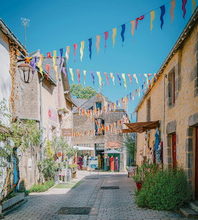 Sunny old street in Guérande with stone buildings and colorful flags hanging overhead