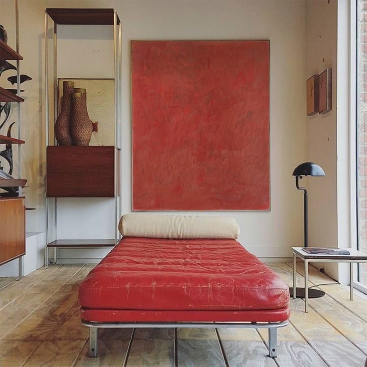 Modern interior with red tufted daybed beneath large red canvas on white wall