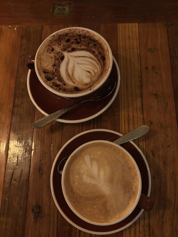 Overhead view of two cups of coffee with latte art on a wooden table