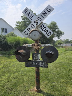Old railroad crossing sign with crossbuck and lights in a green yard