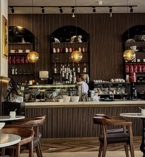 Modern cafe interior with pastry counter, wooden walls, globe pendant lights, and seating
