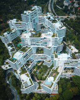 Aerial view of futuristic white curved residential buildings surrounded by forest