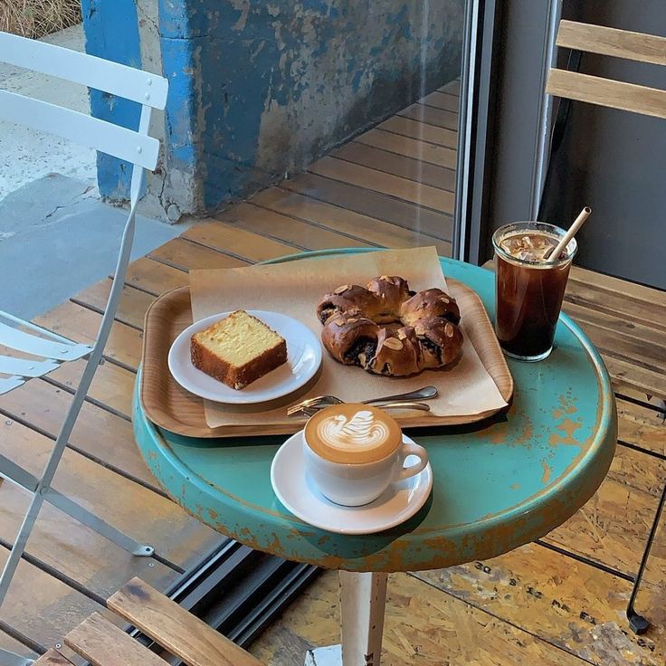 Cafe table with latte art, iced coffee, pound cake, and pastry by a window