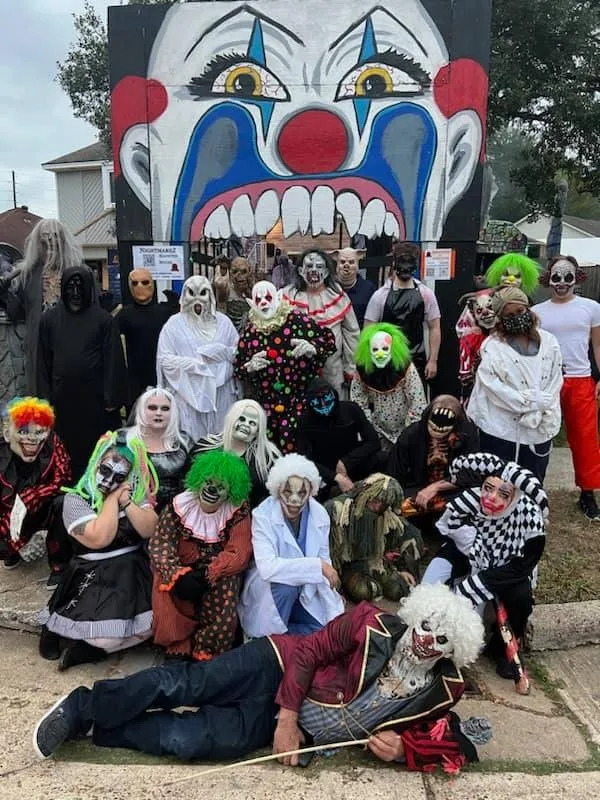 Costumed haunted house crew in scary makeup posing together at night