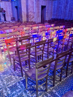 Chapel interior with wooden chairs bathed in colorful stained glass light