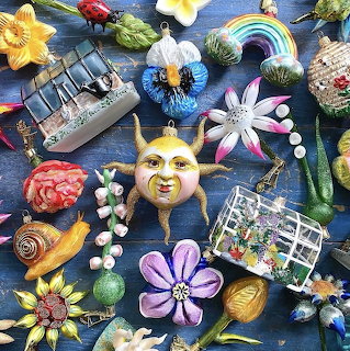 Colorful garden decorations and ornaments arranged in a flat lay composition on dark blue fabric