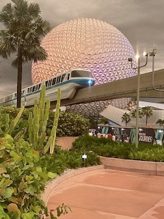 Spaceship Earth dome at EPCOT with monorail train and palm trees in foreground