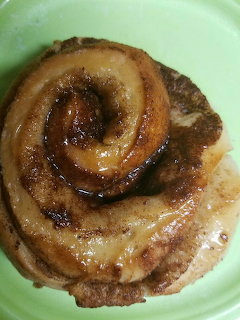 Glazed cinnamon roll with swirled layers on a green plate