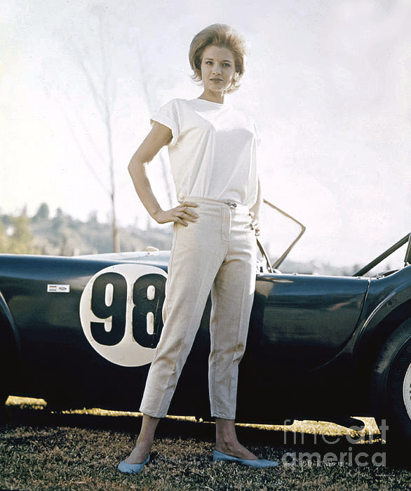 Angie Dickinson standing next to a Shelby Cobra sports car