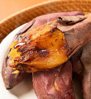Roasted sweet potatoes on a white plate with one split open showing caramelized orange flesh