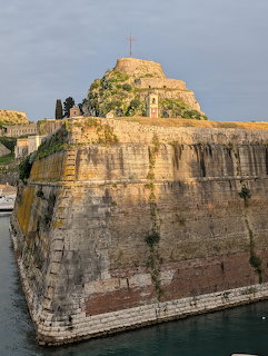 Weathered stone fortress walls surrounded by water moat in Corfu