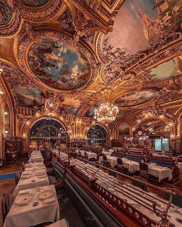 Opulent restaurant interior with ornate golden ceiling paintings, chandeliers, and formal dining setup
