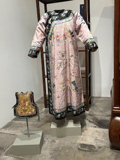 Pink traditional Chinese robe with embroidered floral designs on display stand