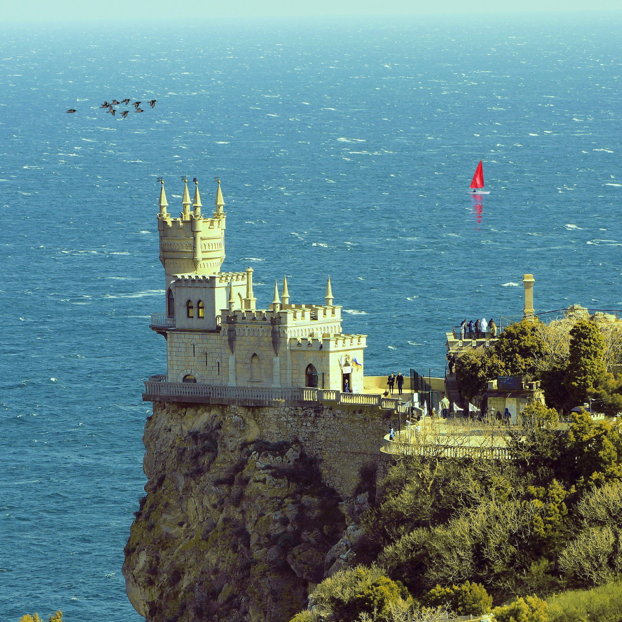 Castle-like building on a rocky seaside cliff above blue water