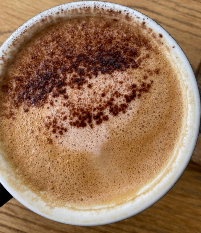 Overhead view of a moccachino with cocoa powder dusting in a white cup on wood table