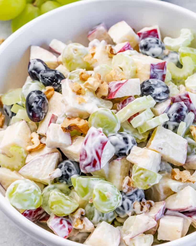 Bowl of Waldorf salad with apples, grapes, celery, and walnuts in creamy dressing
