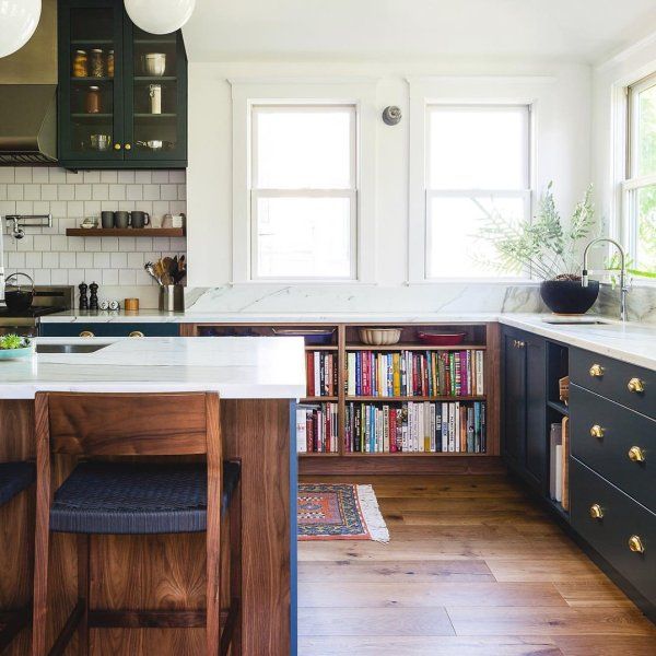 Modern kitchen with dark blue cabinetry, white tile backsplash, wooden island, and bright windows
