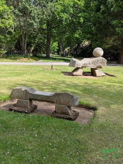 Stone sculptures on a grassy lawn in a tree-lined garden