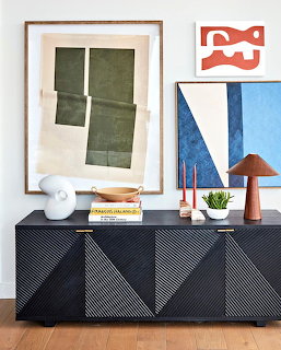 Modern room with a black geometric credenza beneath framed abstract artwork and small decor