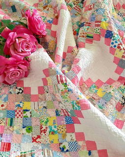 Vintage patchwork quilt with colorful diamond patterns and pink roses on white fabric